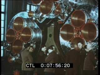 Члены первого отряда космонавтов идут вдоль ракеты в монтажно-испытательном корпусе, слушают разъяснения кураторов