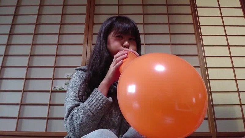 Cute japanese girl blows tight balloons and pops them