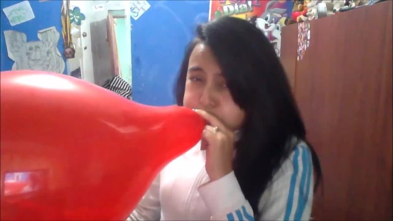Cute girl blowing up a red balloon until it pops and hurts her