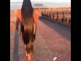 woman with very long hair walking down a bridge