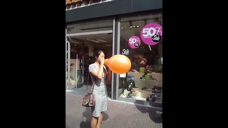 Girl blows to pop orange balloon
