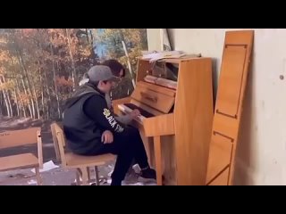 Мальчик учит девочку играть на пианино в разбитой школе