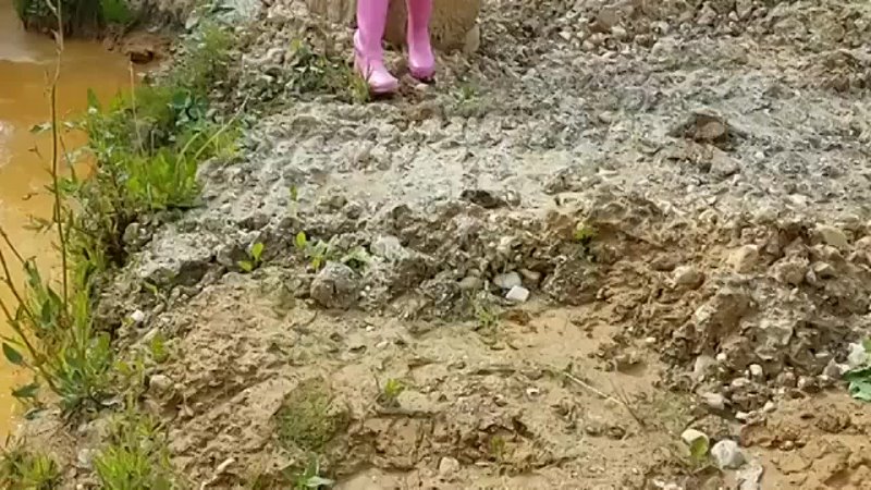 Girl in pink rubber boots in mud