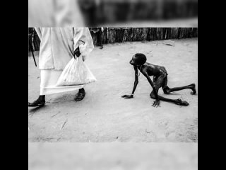 Изнеможённый от голода мальчик ползет за взрослым с мешком еды. Судан, 1998 год.