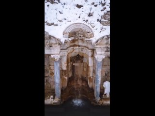 Невероятной красоты действующий античный древнеримский фонтан на фоне зимнего пейзажа