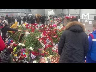 Сотни москвичей и жителей Подмосковья второй день подряд приезжают к стихийному мемориалу возле Крокус Сити Холла. Люди несут