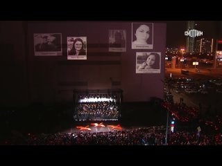 Симфонический оркестр под управлением Валерия Гергиева выступает на сцене у стихийного мемориала рядом с “Крокусом“
