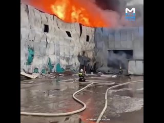 Тушение адского пламени вблизи: пожарные заливают бушующий огонь из шлангов, а стены ангара деформировались и падают от температ