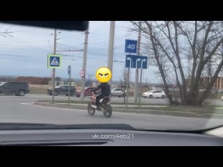 Подросток на мотоцикле без шлема и защиты на оживленном перекрестке