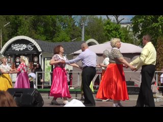 Пожилые люди танцуют танец на сцене в парке