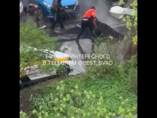 Рабочие кладут асфальт в дождь на Широкой, 21, к. 2.