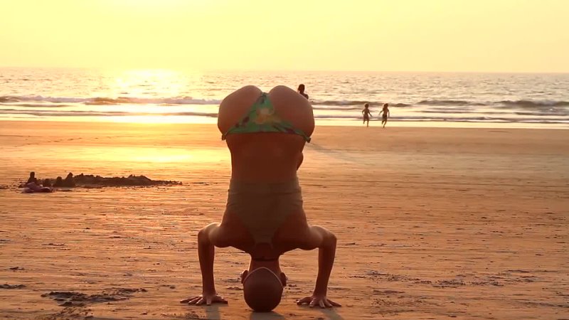 The flexible girl, sandy beach, warm sea and a beautiful sunset