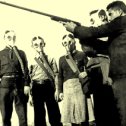 Фотография "Пионервожатый 12-й неполной средней школы г. Батуми обучает пионеров правилам стрельбы в противогазах. СССР, 1938 год."