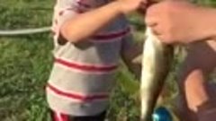Маленький мальчик поймал рыбу на игрушечную удочку