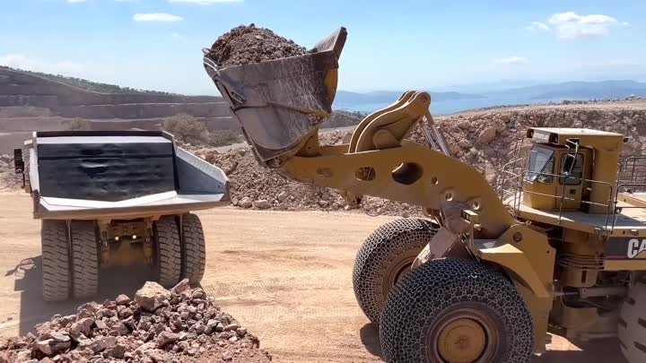 Огромный колесный погрузчик Caterpillar 994 загружает самосвал