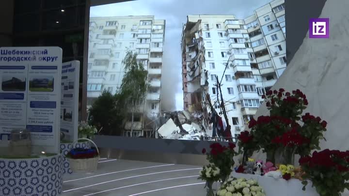 Люди несут цветы в память о погибших к стенду Белгородской области