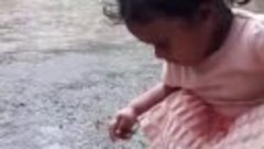 Маленькая девочка наслаждается дождевой водой, любит играть